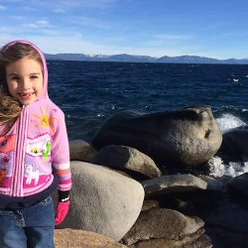 A young girl with brown hair at the Lake Tahoe shoreline